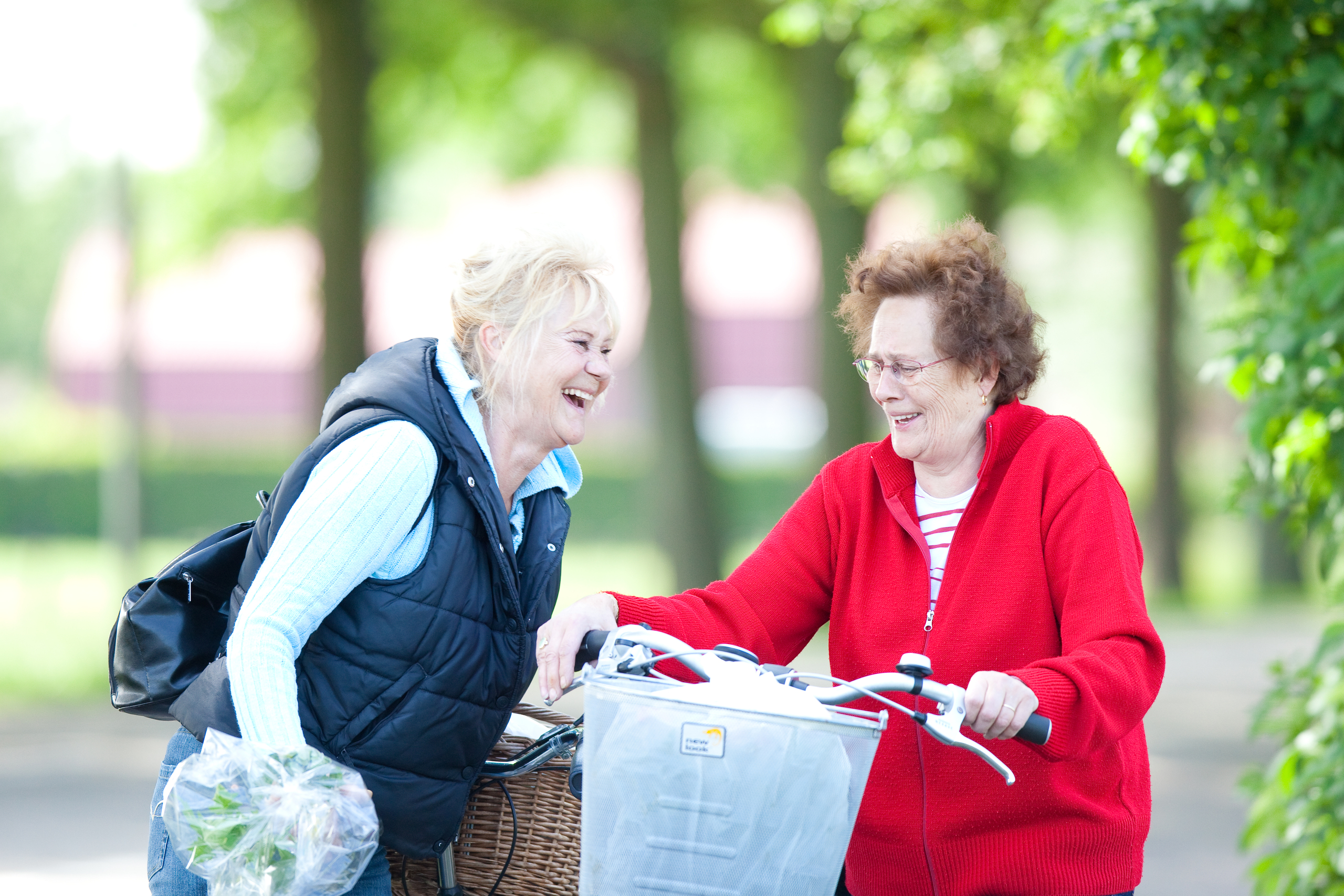 Twee oudere dames lachend met elkaar in gesprek op straat