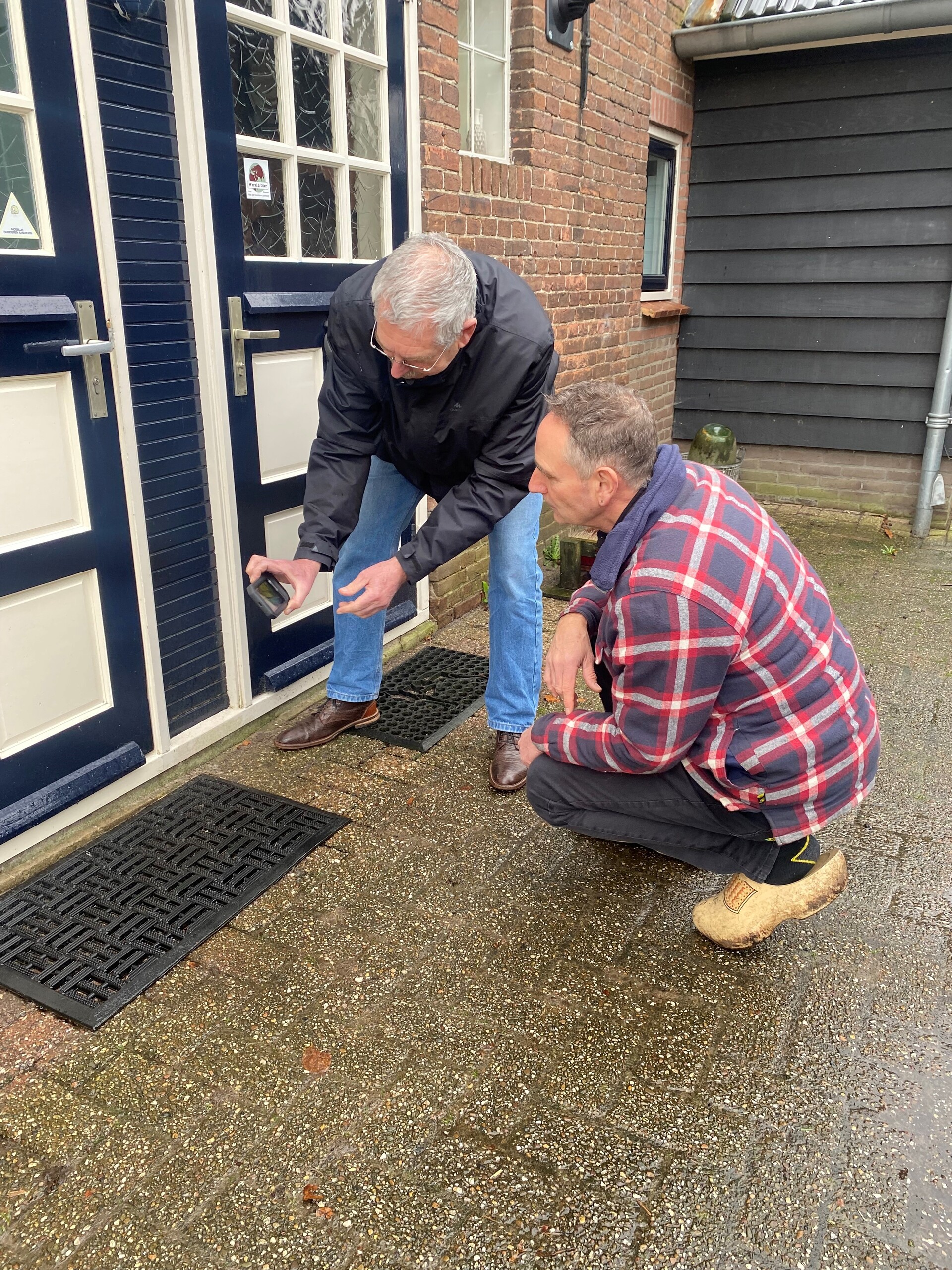 Foto 1 energiecoach Paul en inwoner Maarten staan voor de woning met een meetapparaat