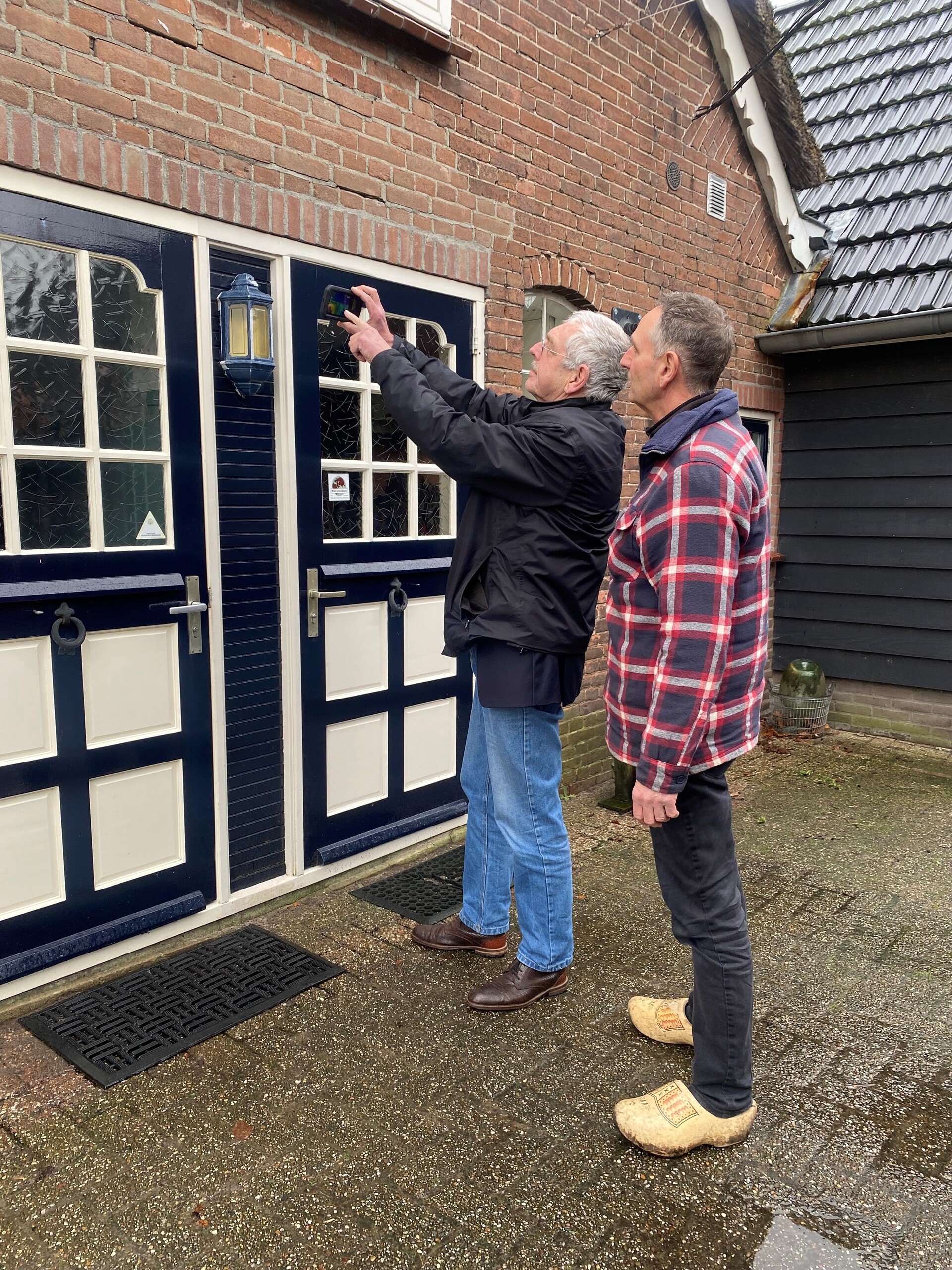 Foto 2 energiecoach Paul en inwoner Maarten staan voor de woning met een meetapparaat