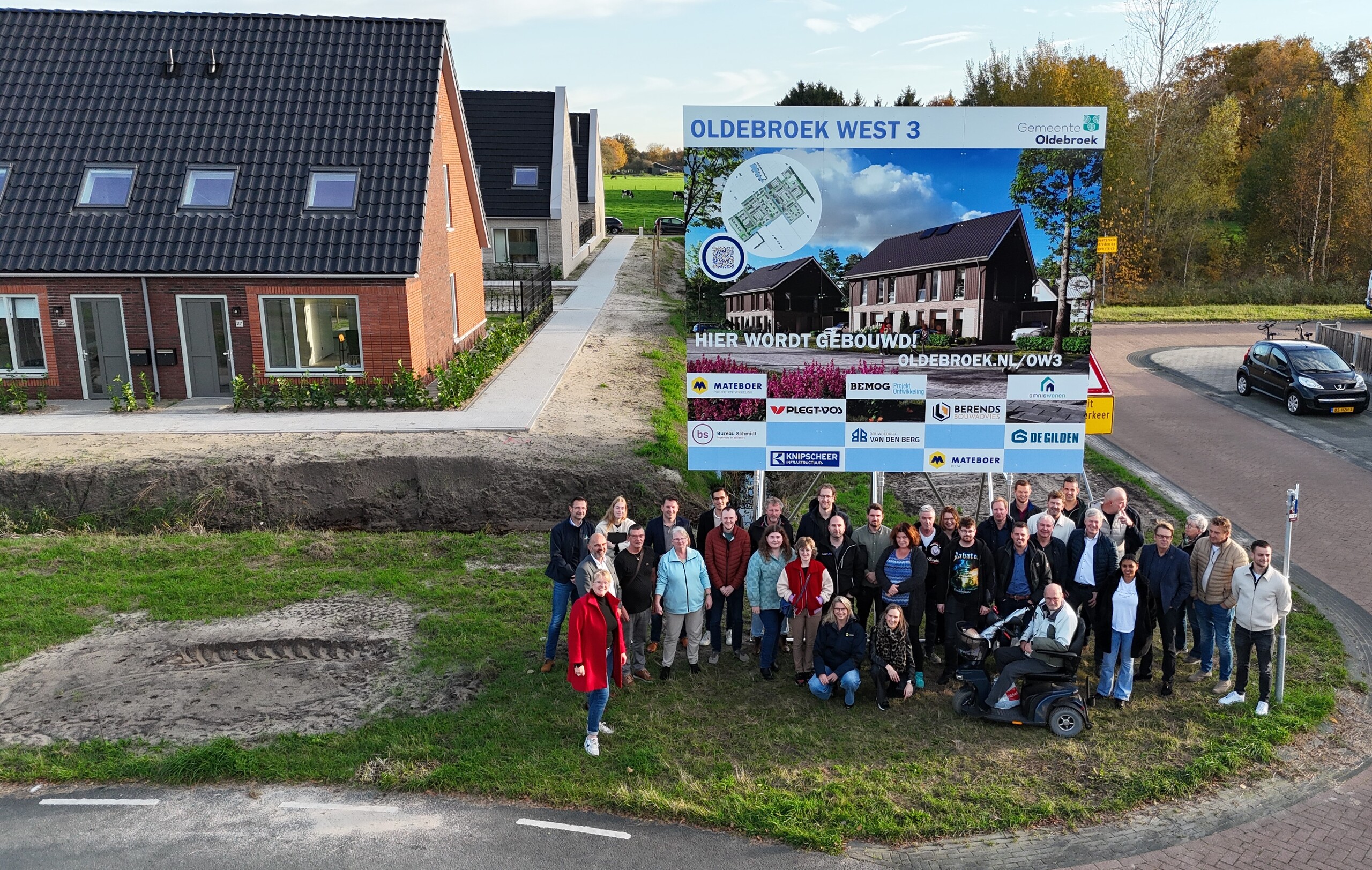 20251106 Nieuwe huurders op de foto bij het bouwbord met de gemeente Oldebroek, Omnia Wonen en diverse bouwpartners