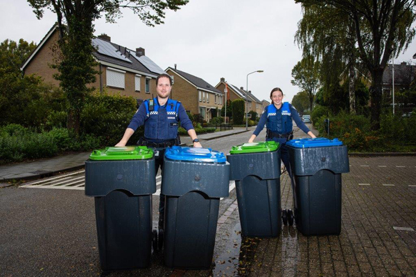 Afvalcoaches Allard en Martine poseren op straat met afvalcontainers