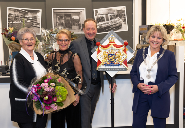 Jenny Vaessen, Henriëtta van Heerde - Vaessen, Dick van Heerde en burgemeester Haseloop-Amsing naast het Koninklijke hofleverancier wapenbord.